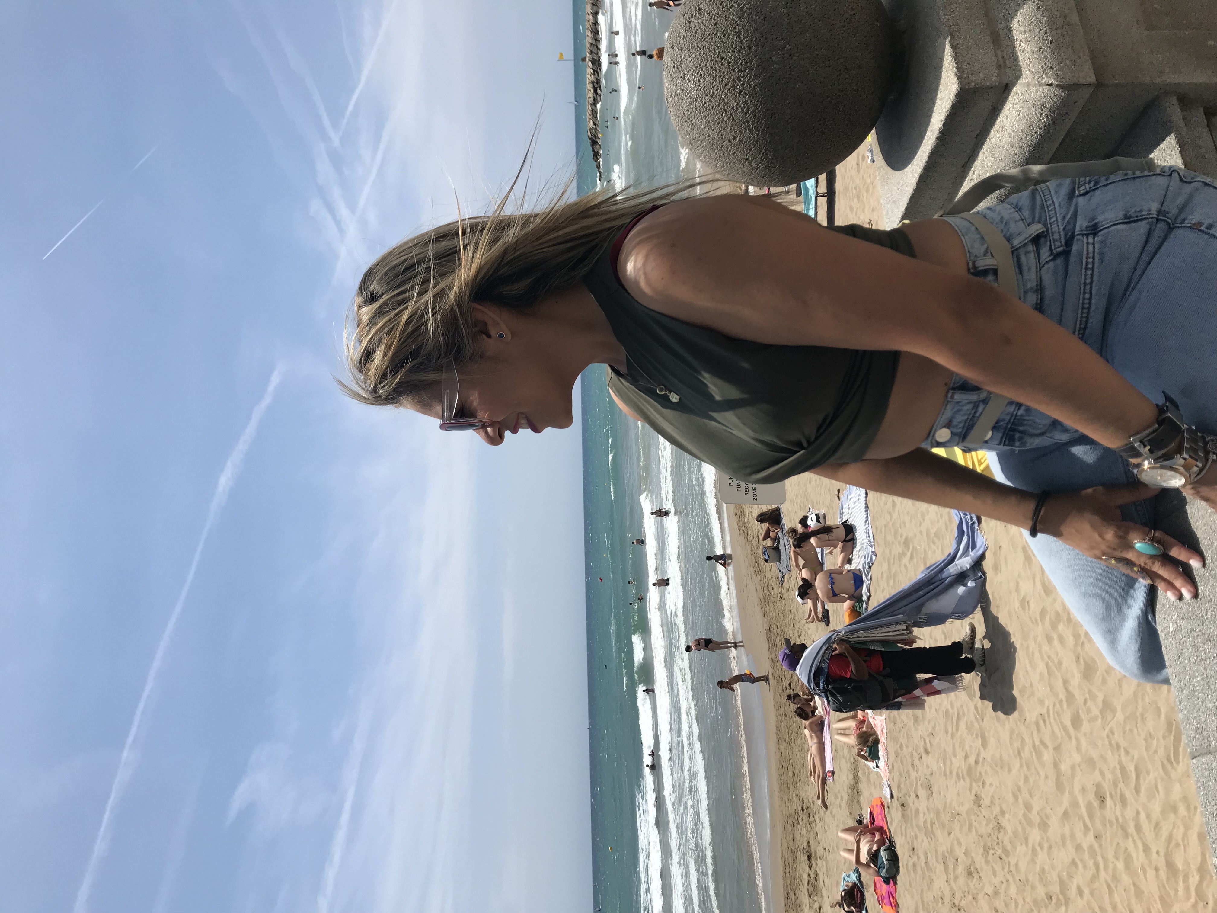 Yfigenia Moreno Aponte mirando al mar en la playa con el viento en el pelo