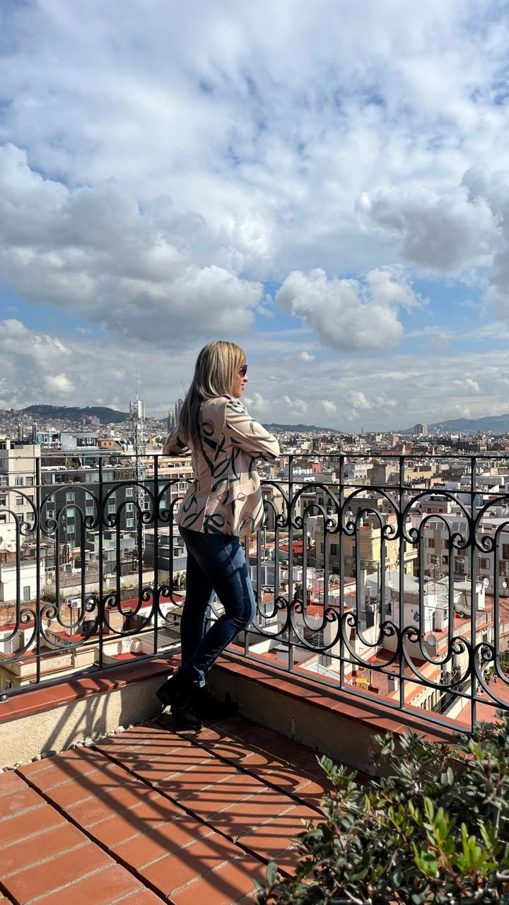 Yfigenia Moreno Aponte mirando el perfil de Barcelona desde una terraza, con la ciudad extendida bajo un cielo con nubes