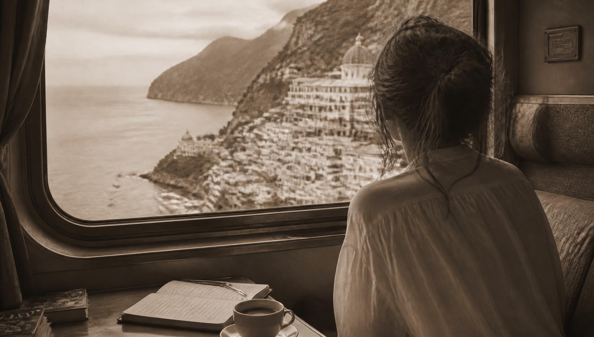 Mujer de espaldas mirando por la ventana de un tren la costa mediterránea, con un cuaderno abierto sobre la mesa